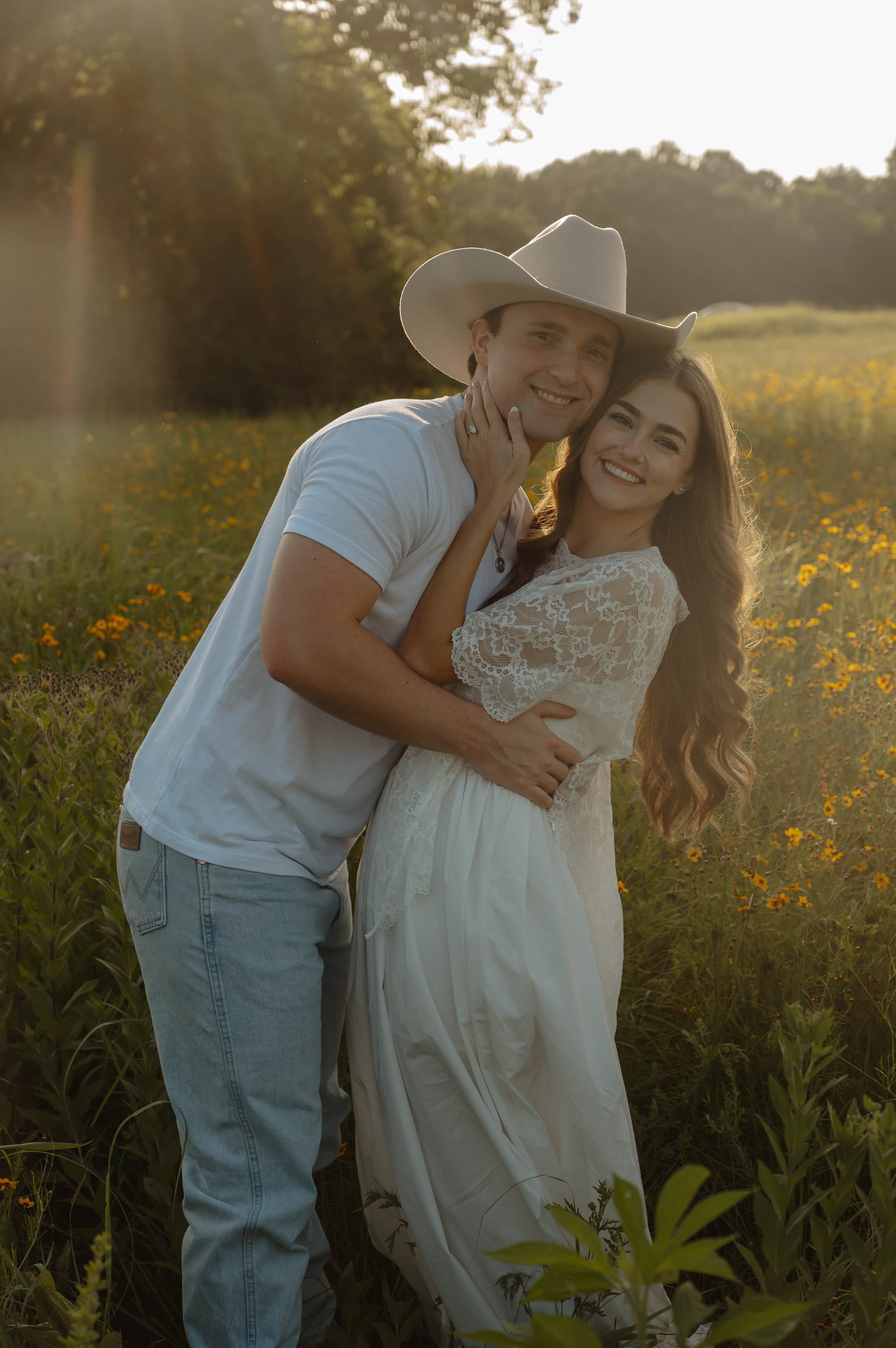 Elise and Tyler smiling together in a field of wildflowers at golden hour