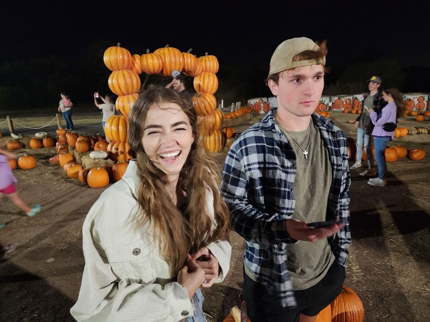 Elise and Tyler in the pumpkin patch at night, lit by string lights