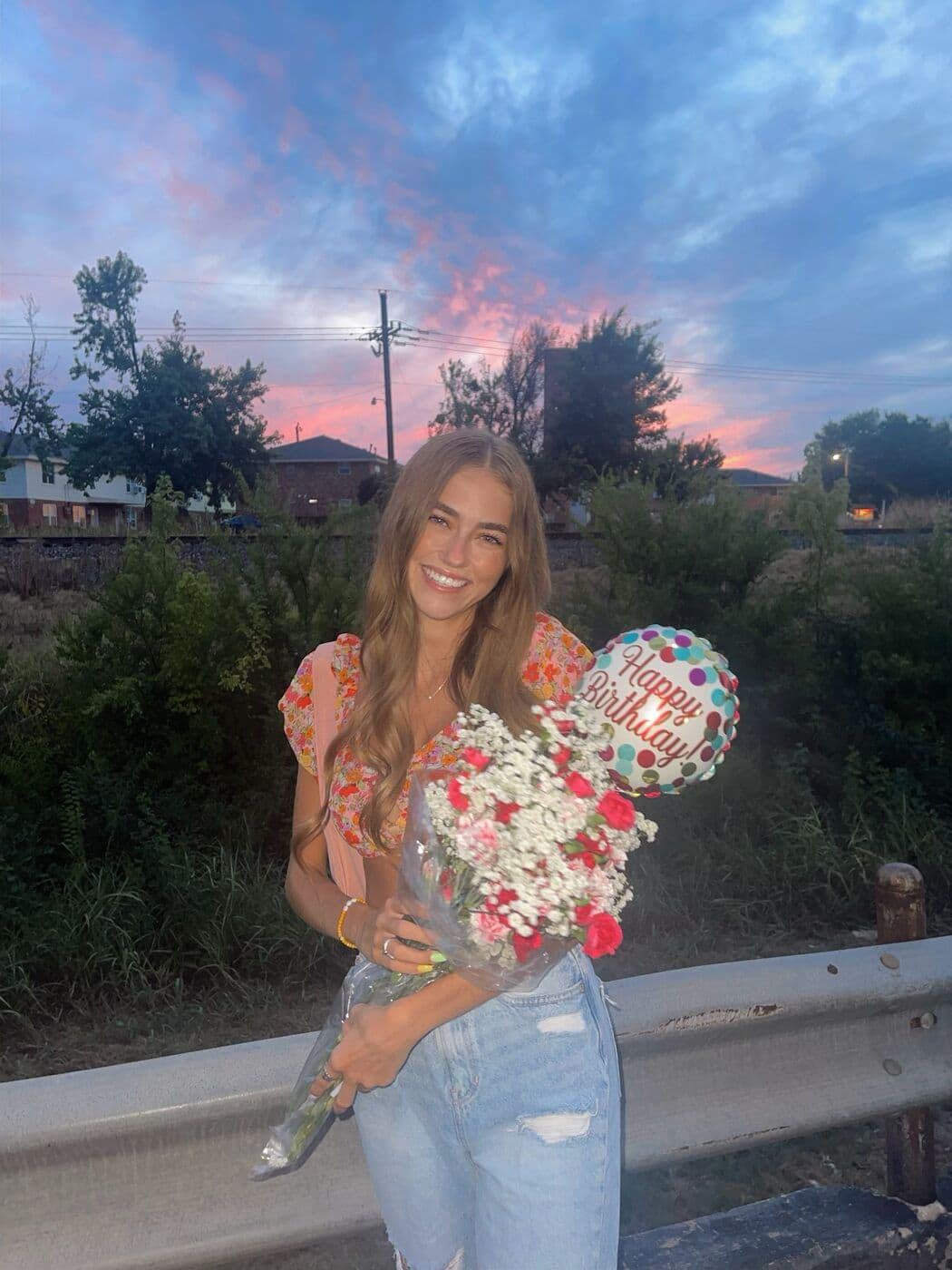 Elise holding a bouquet on a roadside at sunset, from her Hinge profile