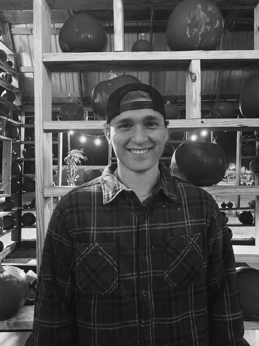 Tyler in a flannel shirt and cap, from his Hinge profile