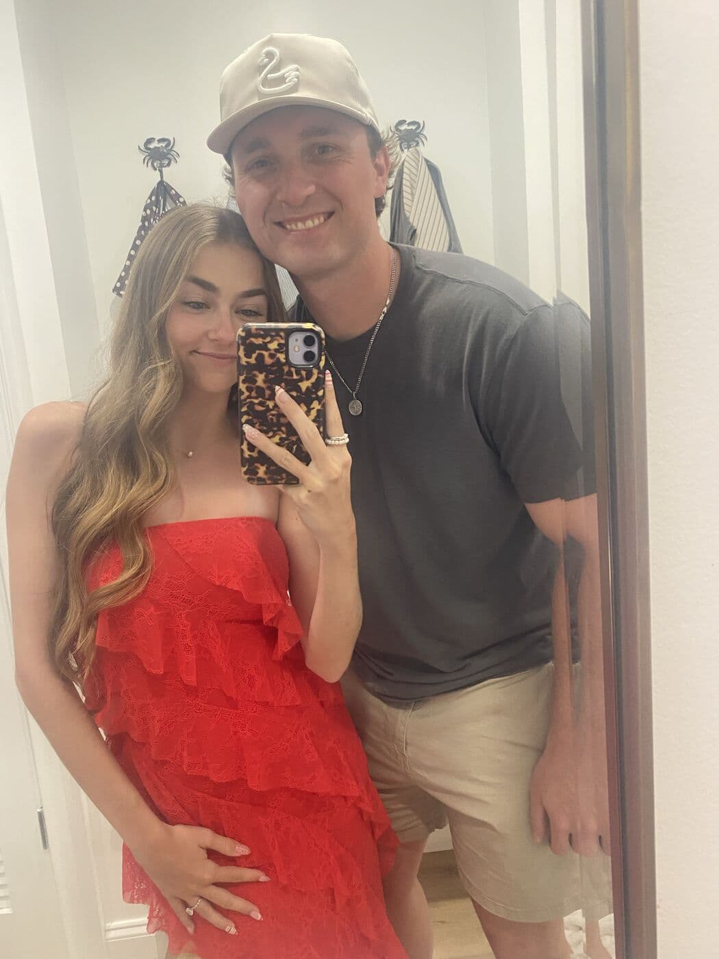 Elise in a red dress and Tyler taking a mirror photo before going out