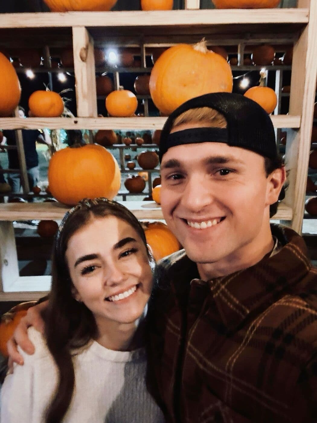 Elise and Tyler in front of shelves of pumpkins at Orr Family Farm